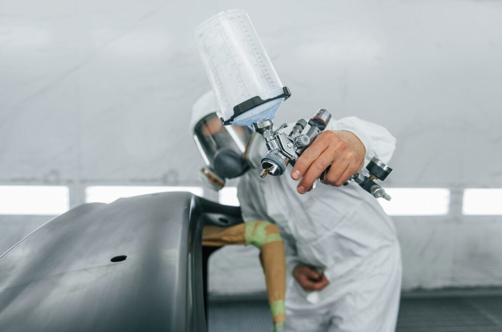 Ready for the painting. Man in uniform is working in the auto service